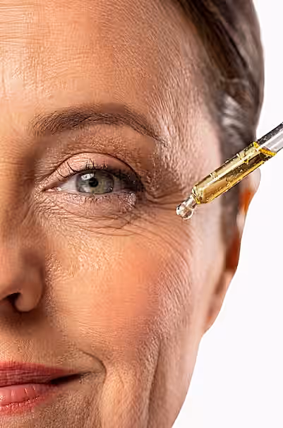 Yaşlı bir kadının yüzüne serum damlalığı ile bakım yağı uygulanıyor.