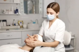 Maske takan bir estetisyen, bir müşterinin yüzüne medikal cilt bakımı uyguluyor.