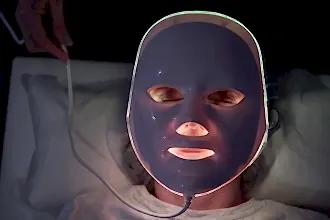 Karanlık bir odada, LED ışıkları yanan bir maske takan bir kişi.